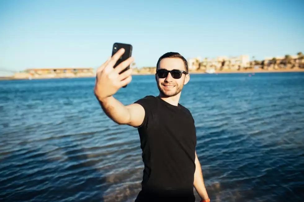 young-handsome-man-doing-self-portrait-with-smartphone-beach