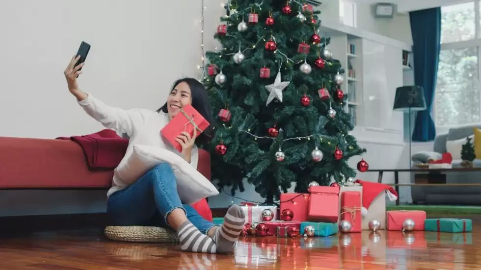 asian-women-celebrate-christmas-festival-female-teen-relax-happy-holding-gift-using-smartphone-selfie-with-christmas-tree-enjoy-xmas-winter-holidays-living-room-home